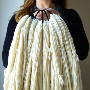 woman holding a large handful of un-dyed non-superwash yarn